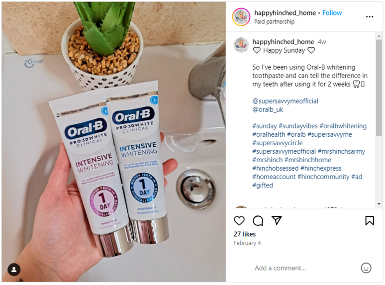 A hand holding two tubes of Oral-B