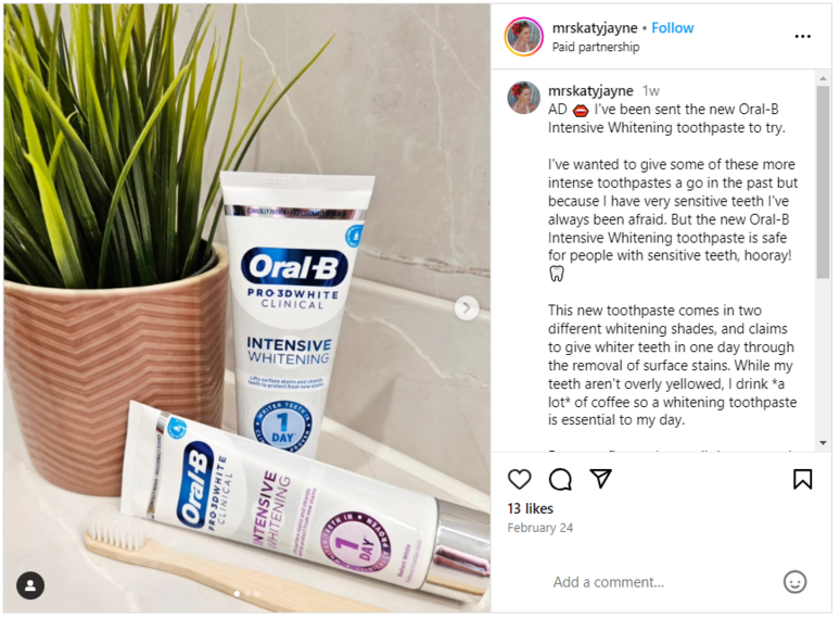 2 Oral-B tubes placed next to a plant