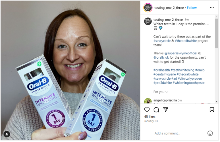 A woman holding two Oral-B tubes while smiling