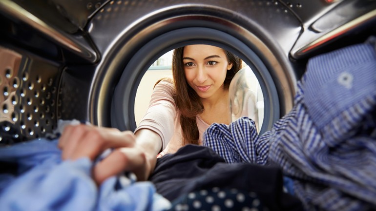 Woman putting clothes in washing machine